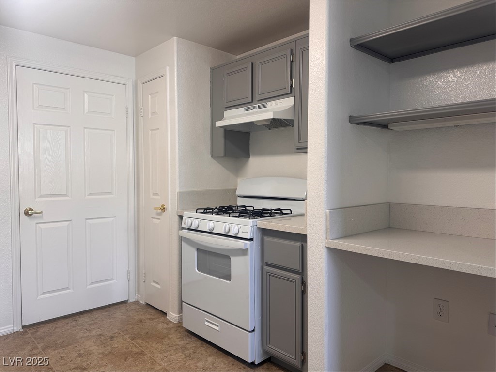 9975 Peace Way, Unit 1140 Las Vegas, NV 89147 - Photo 6 of 23 Kitchen with light countertops, gray cabinetry, exhaust hood, and stove