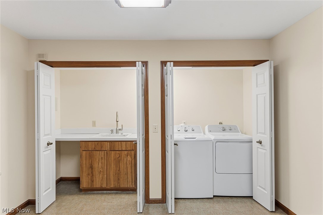 5741 Som Center Road, Unit 1 Solon, OH 44139 - Photo 22 of 50 Dedicated laundry area featuring a utility sink, wood-finish cabinetry, white countertop, and bi-fold doors
