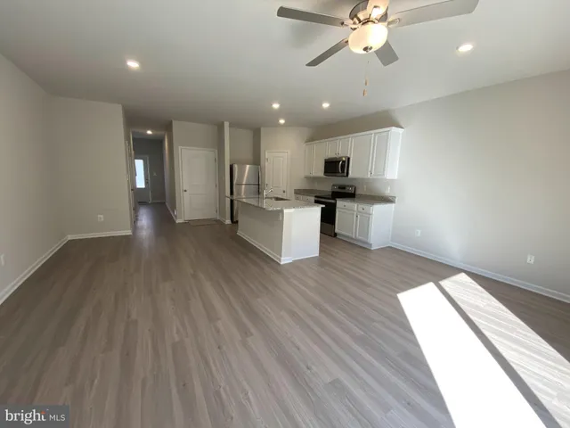 a view of a kitchen with a sink and dishwasher a stove top oven with wooden floor