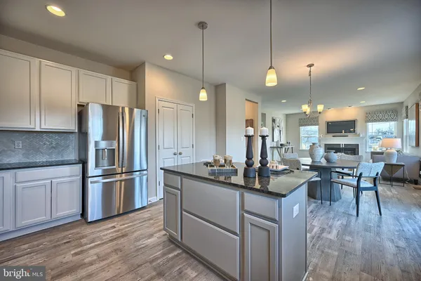 a kitchen with stainless steel appliances granite countertop a stove top oven a sink a dining table and chairs with wooden floor