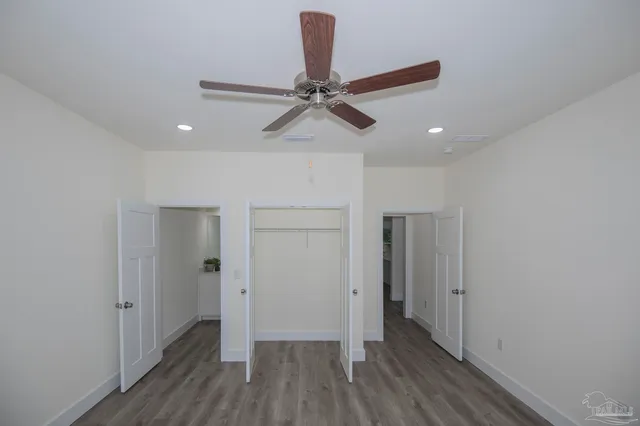 a view of a hallway with a chandelier fan and wooden floor