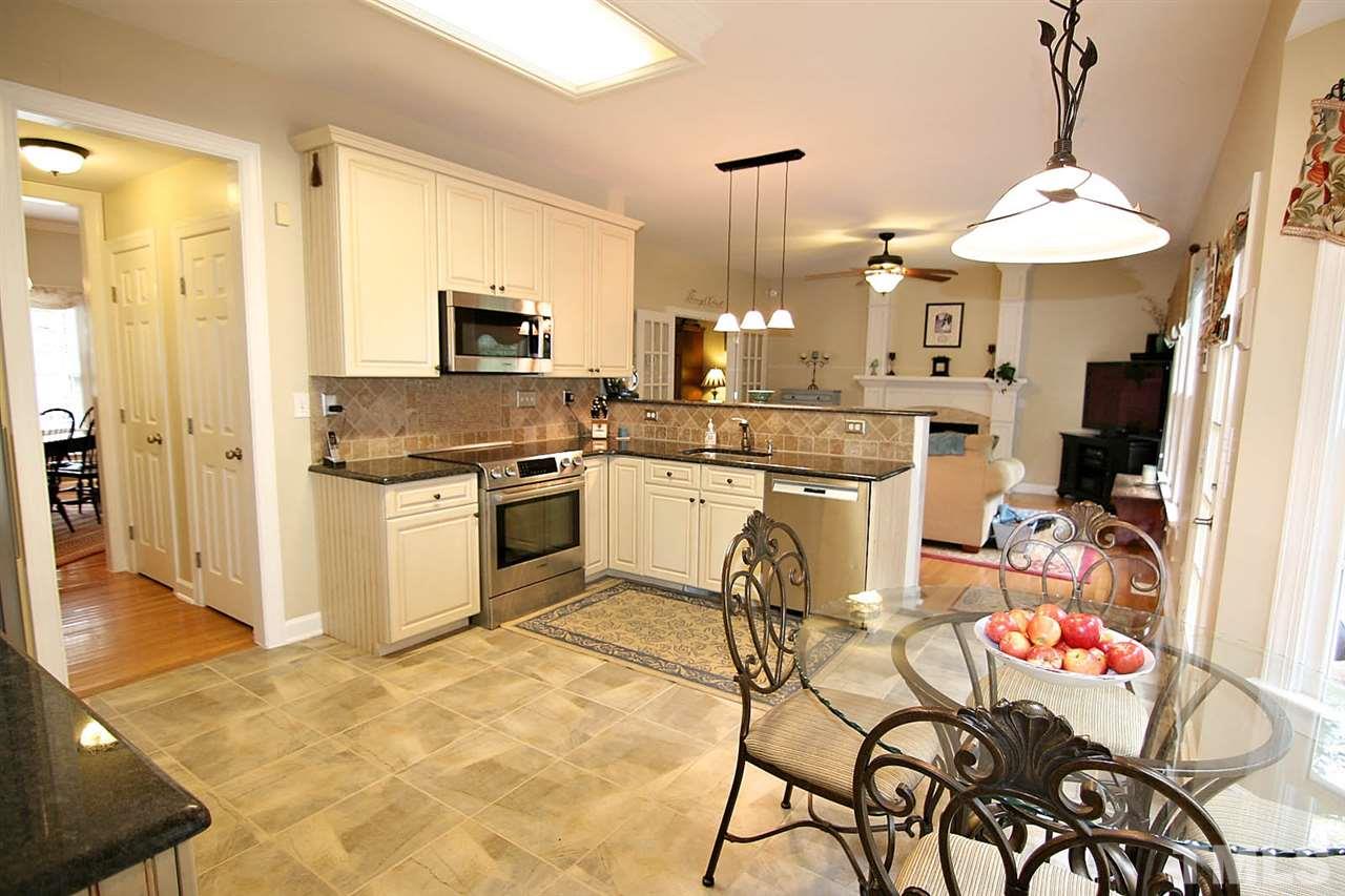 4109 Batiste Road Raleigh, NC 27613 - Photo 11 of 25 a kitchen with stainless steel appliances kitchen island granite countertop a table and chairs in it