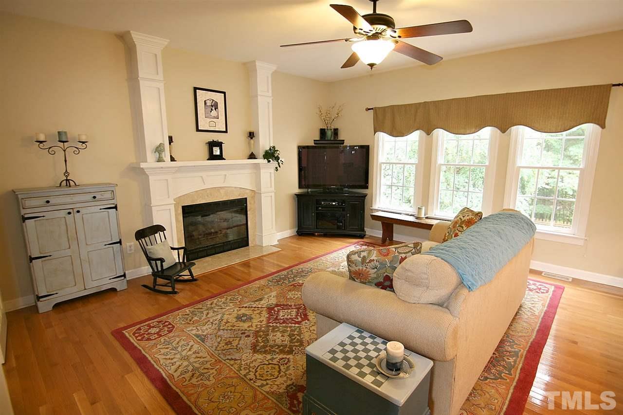 4109 Batiste Road Raleigh, NC 27613 - Photo 8 of 25 a living room with furniture a fireplace and a floor to ceiling window