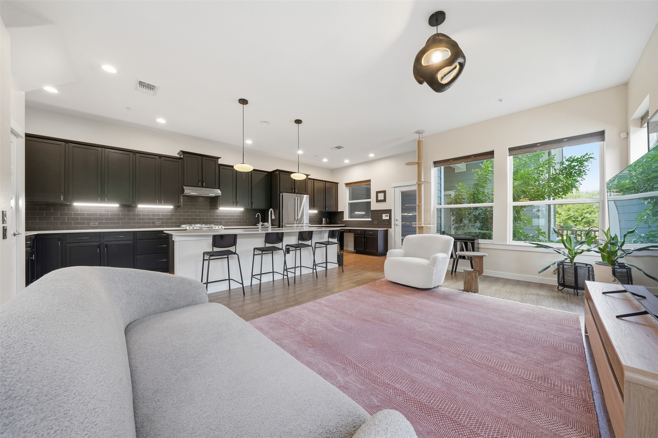 3901 Vaughan Street Austin, TX 78723 - Photo 8 of 37 Open-concept living space featuring a kitchen with dark cabinetry, a subway tile backsplash, and a large island with pendant lighting