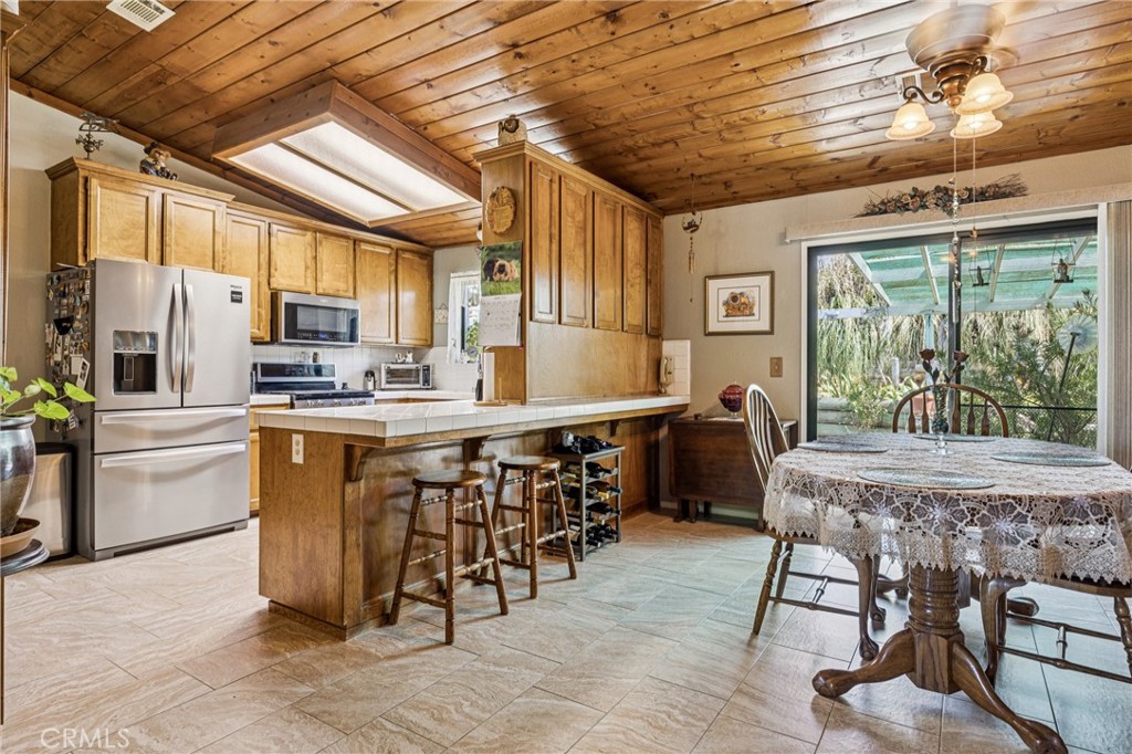 7050 Shale Rock Road Paso Robles, CA 93446 - Photo 5 of 45 a dining hall with stainless steel appliances granite countertop a stove a refrigerator a oven with a dining table and chairs with wooden floor