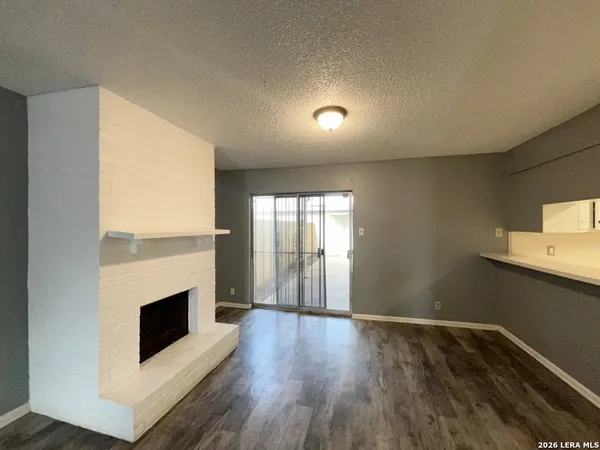an empty room with wooden floor fireplace and windows