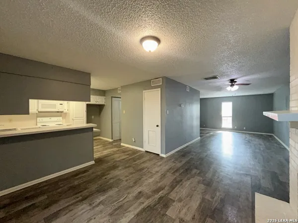 a view of an empty room with window and wooden floor