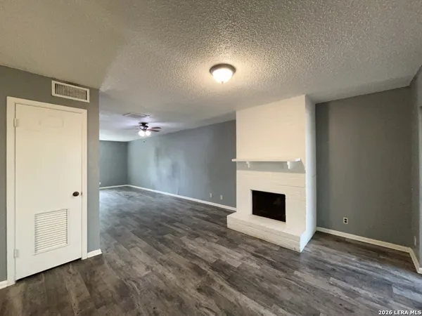 an empty room with wooden floor fireplace and windows