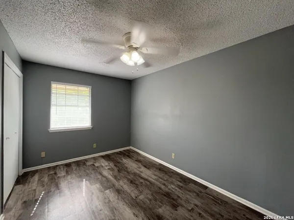 an empty room with a window and chandelier fan