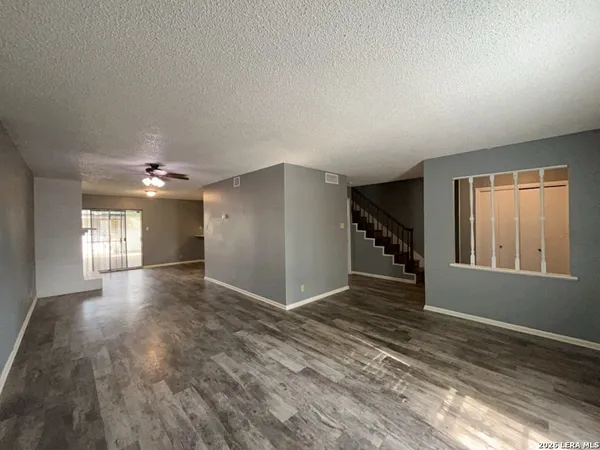 a view of an empty room with a window and wooden floor
