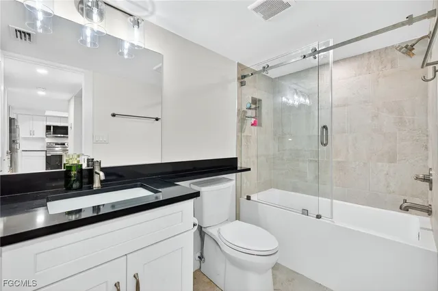 a bathroom with a granite countertop sink toilet a shower and a mirror