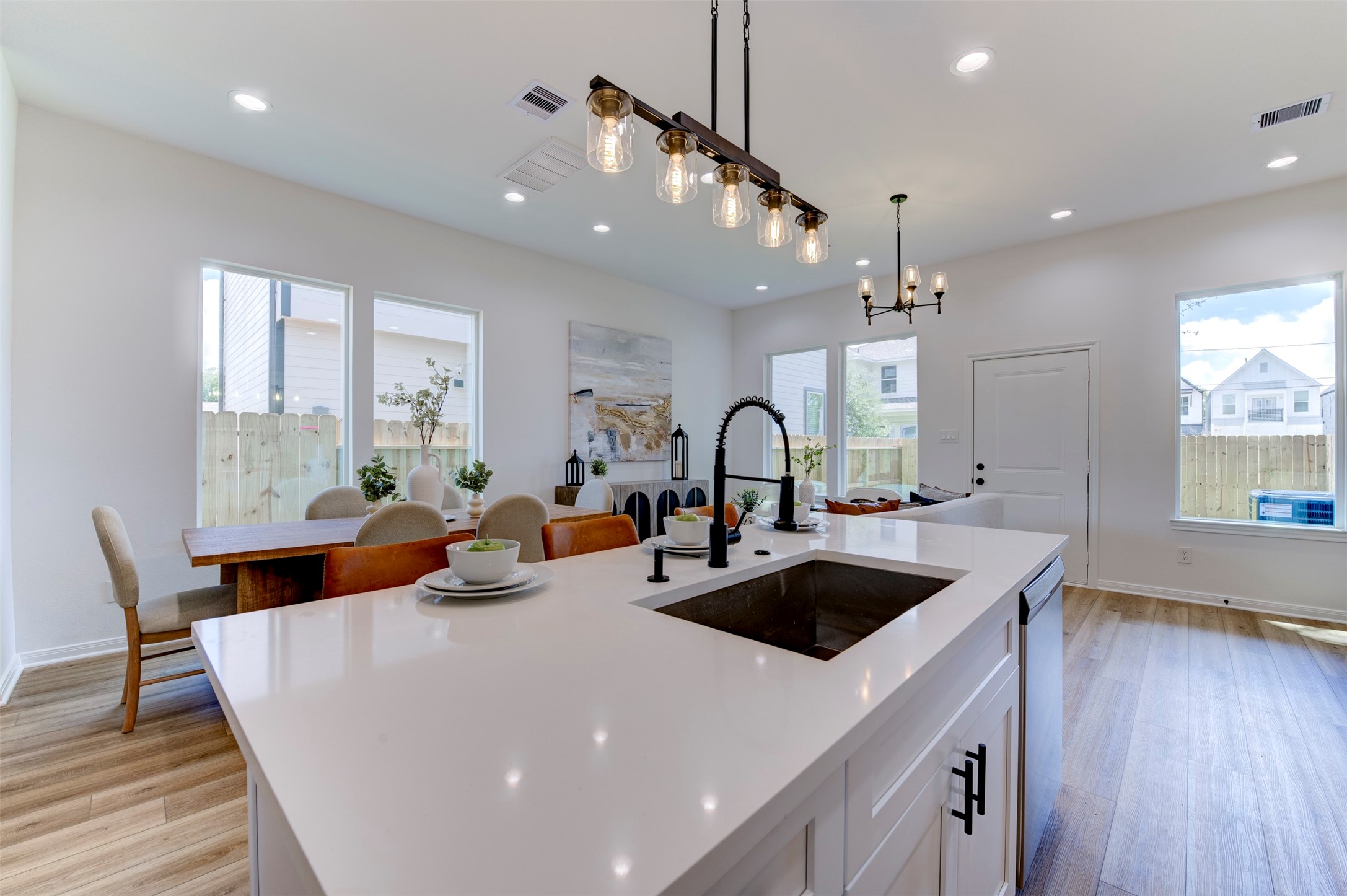 6807 Paris Street Houston, TX 77021 - Photo 18 of 50 Kitchen island detail with quartz countertop, farmhouse sink, matte black coil-spring faucet, Edison rail pendant, and open view through to dining area and rear windows with yard and street views.