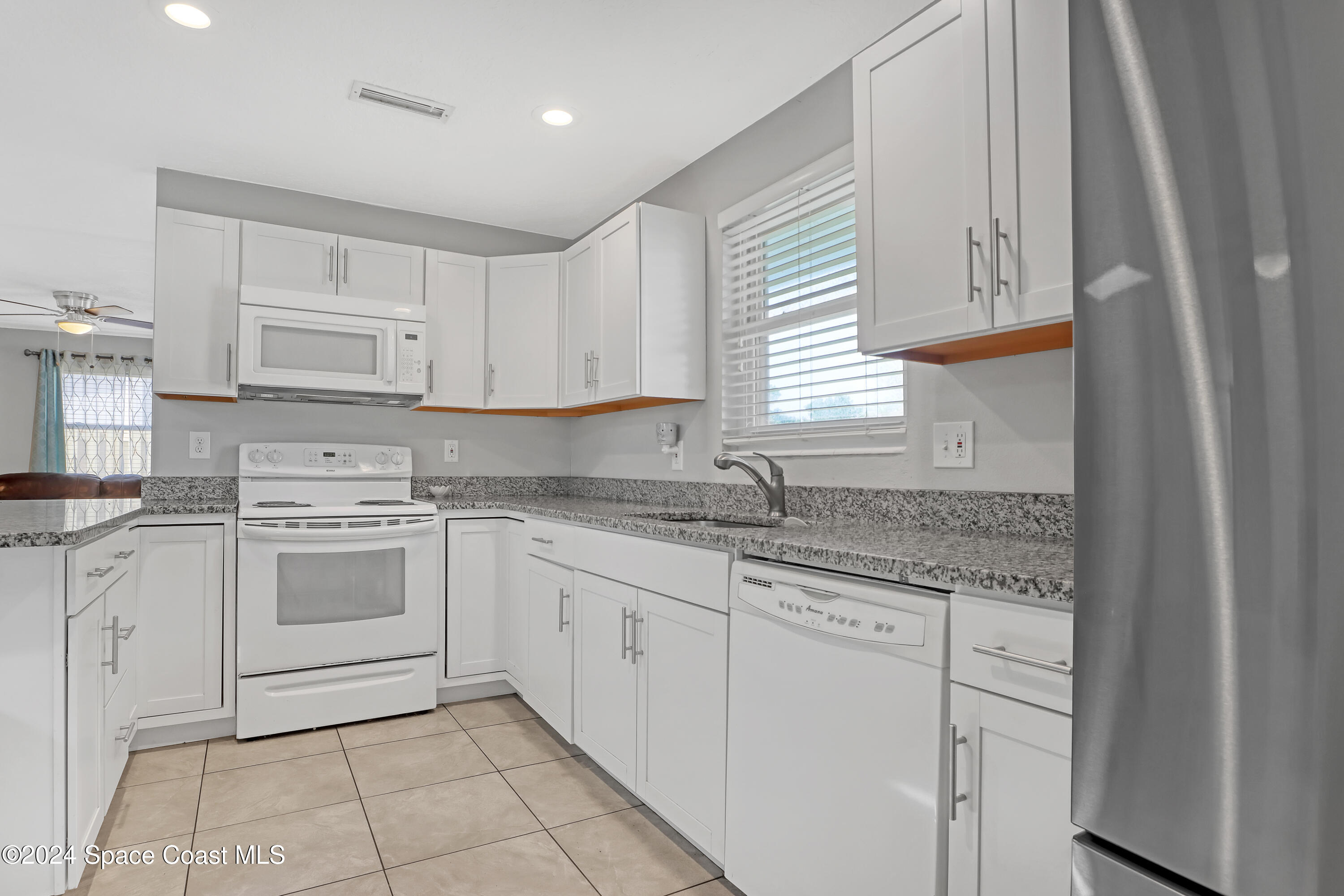 2581 Locksley Road Melbourne, FL 32935 - Photo 13 of 33 a kitchen with granite countertop white cabinets and white appliances