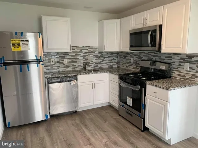 a kitchen with cabinets appliances and a wooden floor