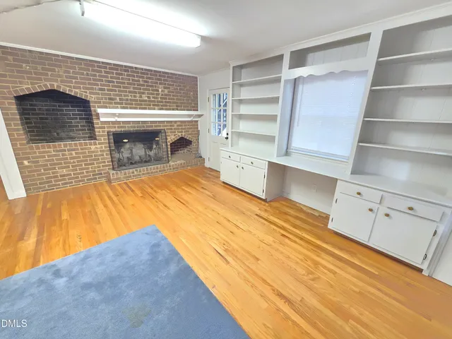 a view of empty room with wooden floor and fireplace