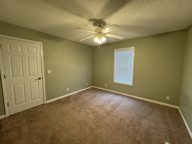 an empty room with a ceiling fan and a window