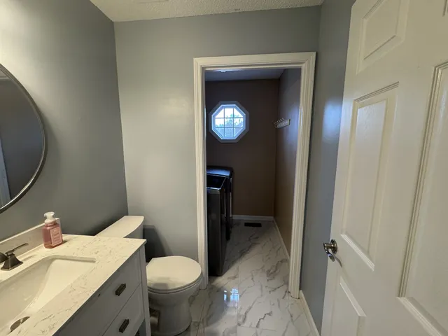 a bathroom with a toilet sink vanity and mirror