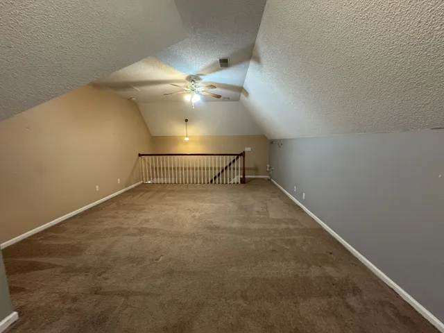 an empty room with a ceiling fan and carpet