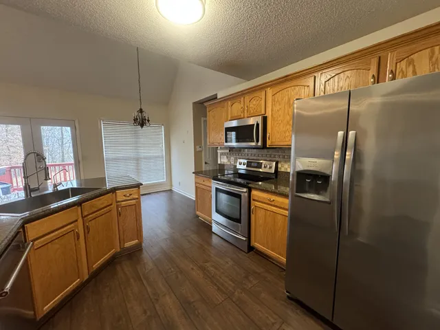 a kitchen with stainless steel appliances granite countertop a refrigerator a stove top oven a sink and dishwasher