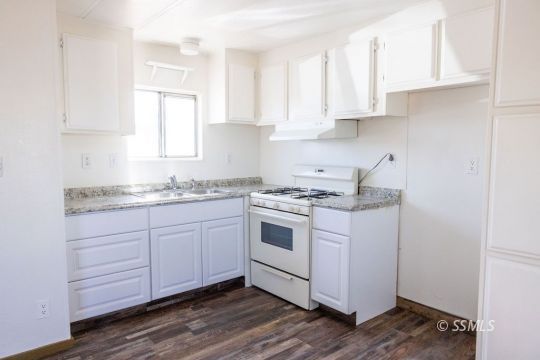 1249 North Charles Street Ridgecrest, CA 93555 - Photo 10 of 21 a kitchen with granite countertop white cabinets and white appliances