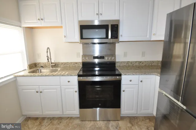 a kitchen with granite countertop white cabinets and stainless steel appliances