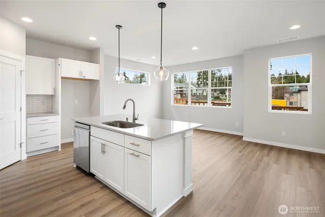 a kitchen with stainless steel appliances granite countertop a sink a stove and a wooden floor