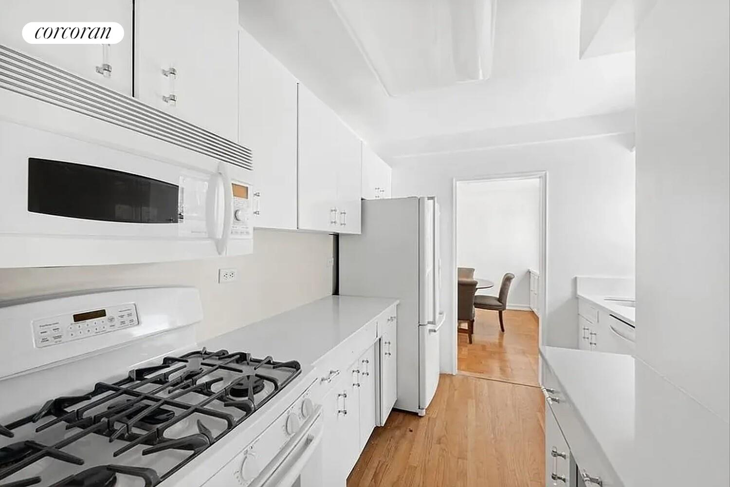 40 East 78th Street, Unit 10B Manhattan, NY 10075 - Photo 4 of 9 a kitchen with stainless steel appliances a stove a sink a refrigerator wooden floor and cabinets
