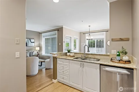 a dining hall with granite countertop a stove a sink and white cabinets with wooden floor