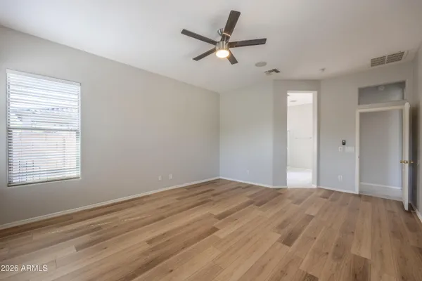 a view of empty room with wooden floor and ceiling fan