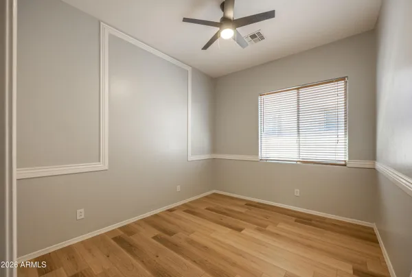 a view of empty room with wooden floor and fan