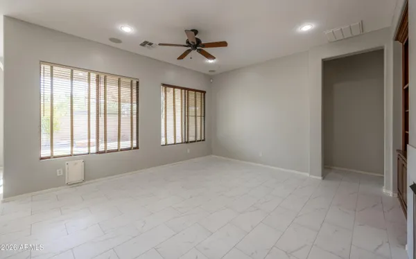 an empty room with windows and chandelier fan