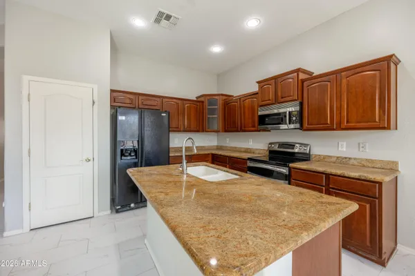 a kitchen with stainless steel appliances granite countertop a sink dishwasher stove top oven and wooden cabinets