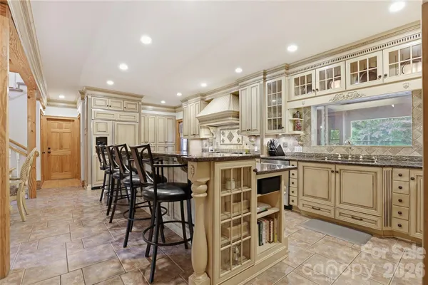 a kitchen with stainless steel appliances kitchen island granite countertop a table chairs sink and cabinets