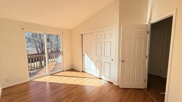 an empty room with wooden floor and windows