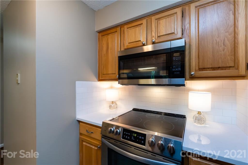 5003 Sharon Road, Unit G Charlotte, NC 28210 - Photo 18 of 42 a kitchen with granite countertop a stove top oven microwave and cabinets