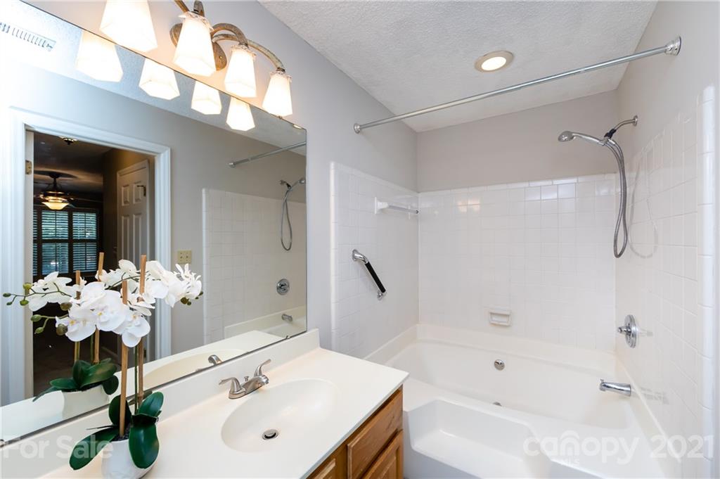 5003 Sharon Road, Unit G Charlotte, NC 28210 - Photo 32 of 42 a bathroom with a sink mirror and a bathtub with shower