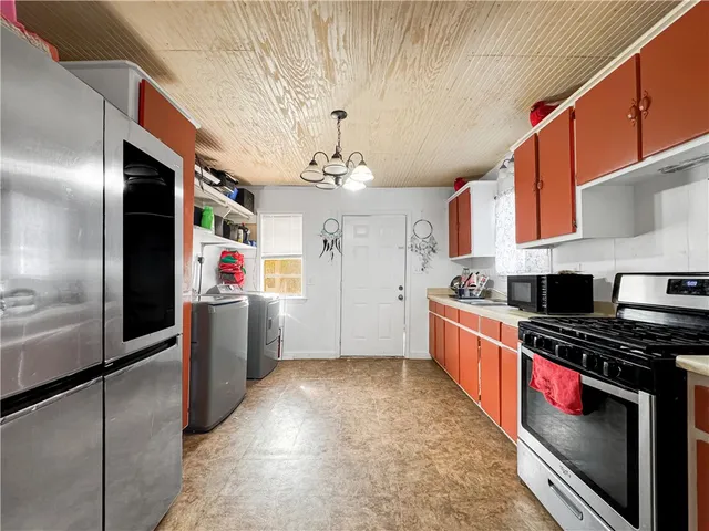 a kitchen with stainless steel appliances a refrigerator a sink dishwasher a stove and a dining table with wooden floor