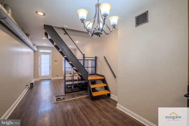 a view of a room with wooden floor staircase and a chandelier
