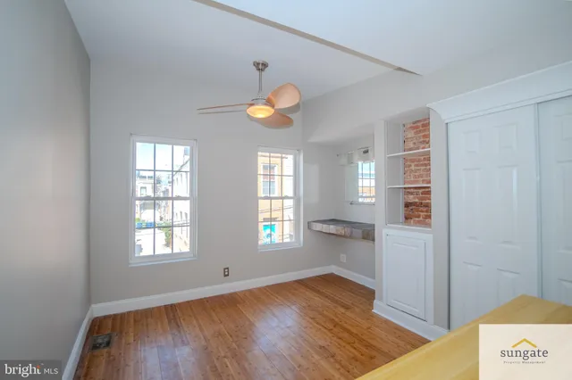 a view of an empty room with window and wooden floor