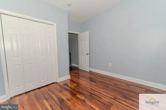 a view of an empty room with closet and wooden floor