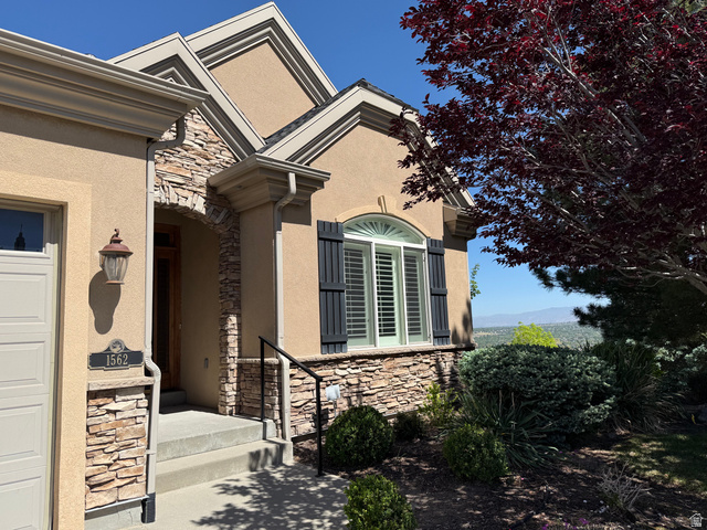 1562 Fairway Ridge Road Draper, UT 84020 - Photo 2 of 60 Stucco exterior with stone accents, featuring an arched entryway with a wooden door and a decorative sconce