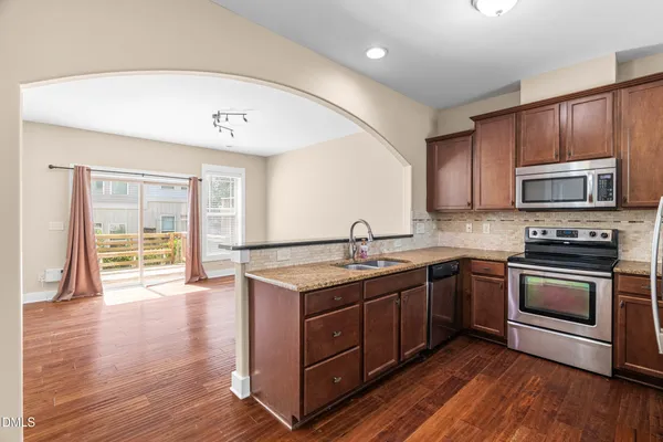 a kitchen with stainless steel appliances granite countertop a stove a sink and a microwave