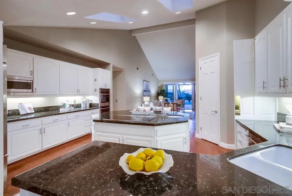 16157 Country Day Road Poway, CA 92064 - Photo 38 of 70 a large kitchen with kitchen island granite countertop a sink a stove counter space and cabinets