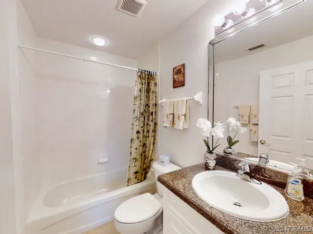a bathroom with a granite countertop sink a toilet and shower
