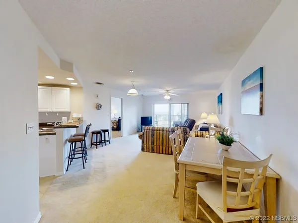 a living room with furniture kitchen view and a wooden floor