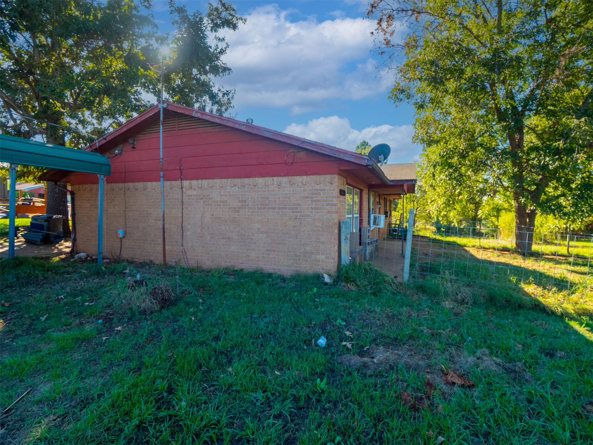 1599 North 4010 Road Boswell, OK 74727 - Photo 41 of 57 Brick exterior with a red gable roof, covered side entry, and mature trees