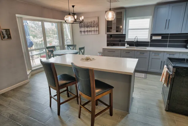 a kitchen with stainless steel appliances granite countertop a kitchen island hardwood floor sink stove dining table and chairs