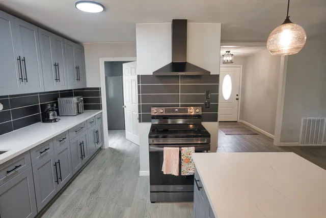 a kitchen with stainless steel appliances a stove a chimney a sink and cabinets