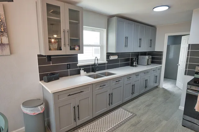 a kitchen with white cabinets and sink