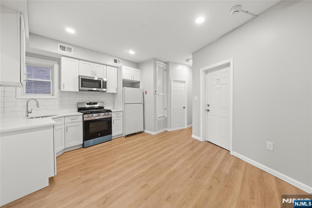 53 Henry Street, Unit D2 Passaic, NJ 07055 - Photo 8 of 12 a kitchen with kitchen island a sink stainless steel appliances and cabinets